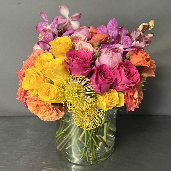 Colorful bouquet of roses and orchids in a clear glass vase