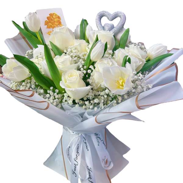 White tulips and roses in a wrapped bouquet with a heart topper.