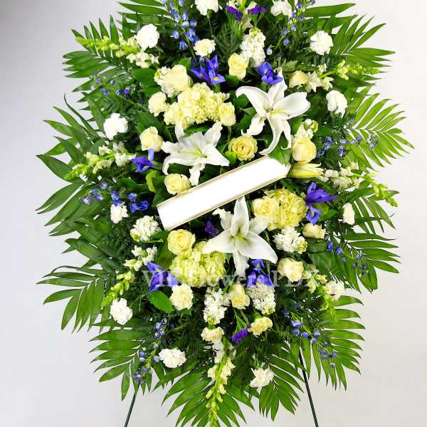 Large standing funeral wreath with white lilies and pale yellow roses