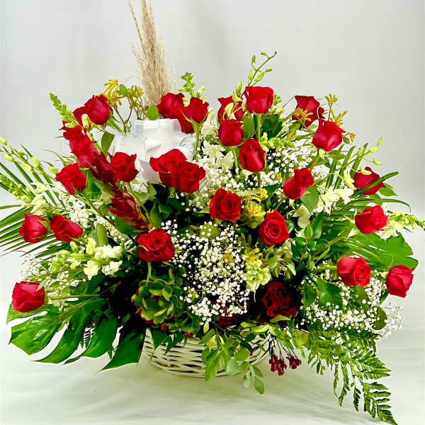 Basket arrangement of red roses with white filler flowers and greenery