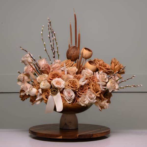 Low floral arrangement of peach and cream roses in a pedestal bowl