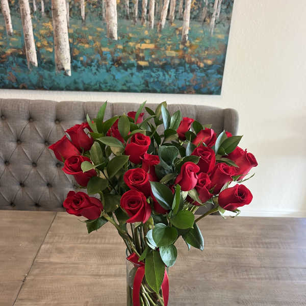 Red roses in a clear glass vase with a red ribbon