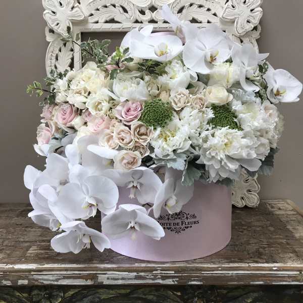 White orchids and pastel roses in a pink hatbox