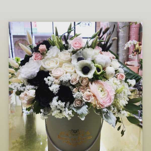 Large mixed bouquet in a round hatbox with pink, white, and black blooms