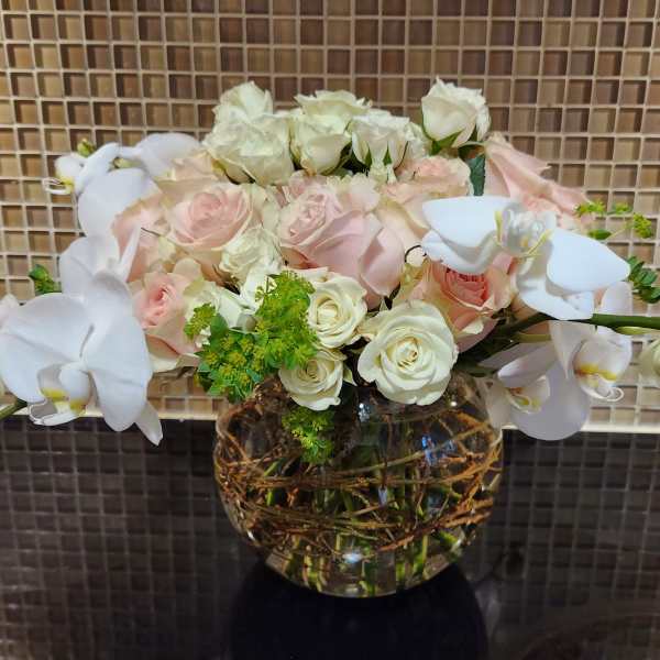 White orchids and pale roses arranged in a glass vase