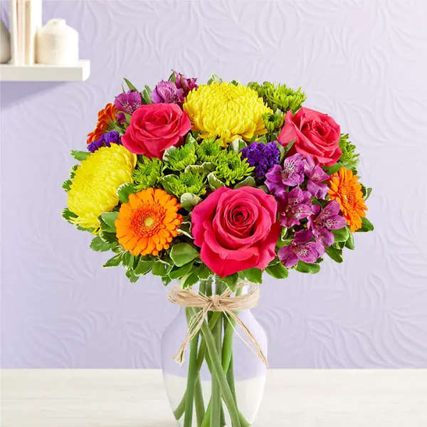 Colorful bouquet of roses, chrysanthemums, and gerbera daisies in a glass vase