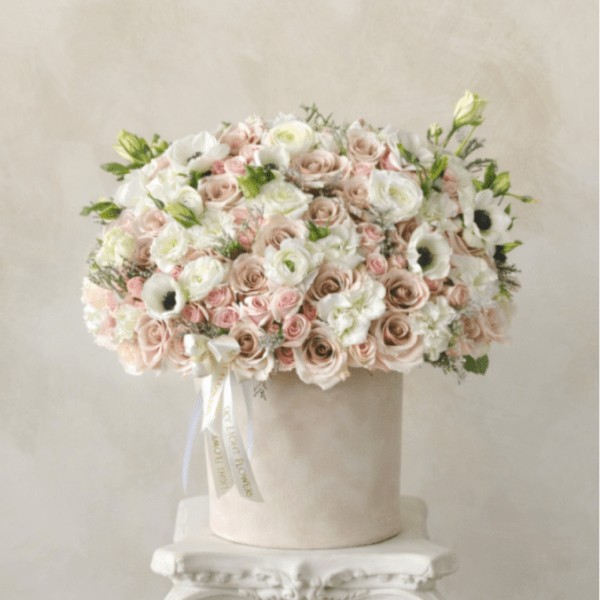 Large pastel rose arrangement in a round box on a pedestal