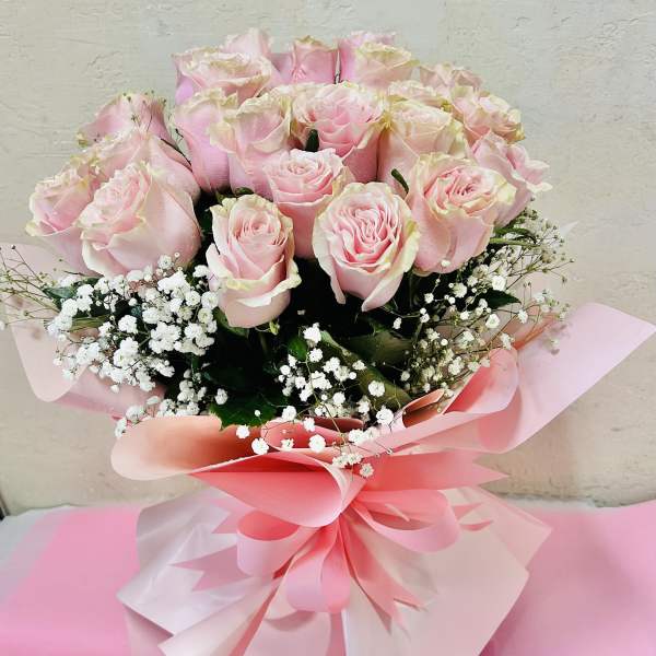 Bouquet of pale pink roses with white baby's breath in pink wrapping