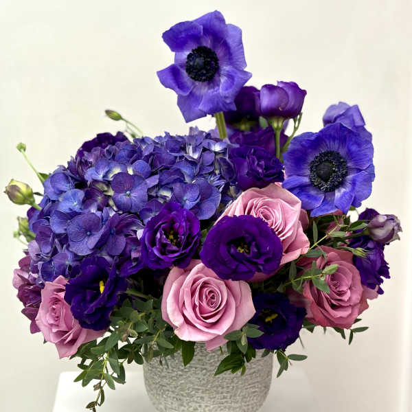Purple and pink floral arrangement in a textured gray vase