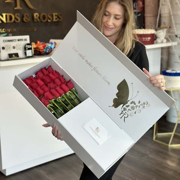 Box of red roses held open by a woman