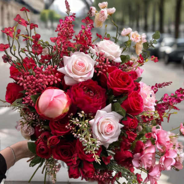 Handheld bouquet of red and blush roses with pink filler flowers