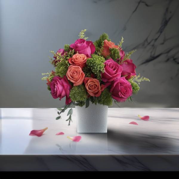 Pink and coral roses arranged in a white square vase