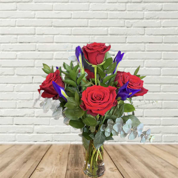 Red roses and purple iris in a clear glass vase