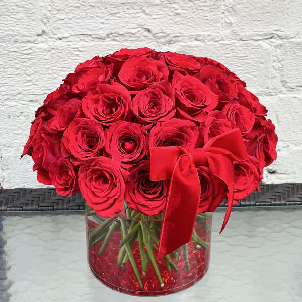 Red rose bouquet in a clear round vase with a red ribbon