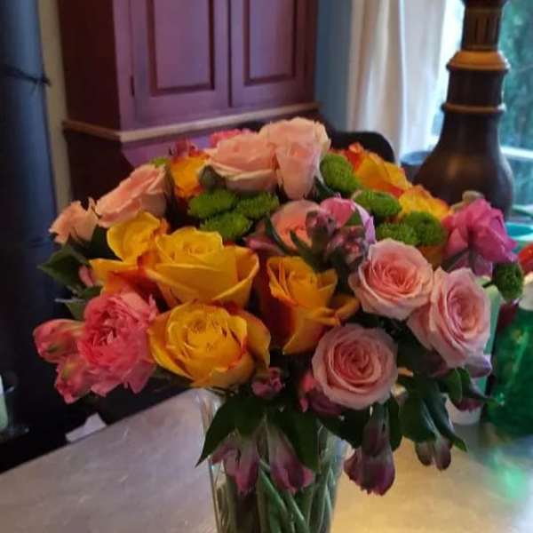 Mixed bouquet of pink and yellow roses in a clear glass vase