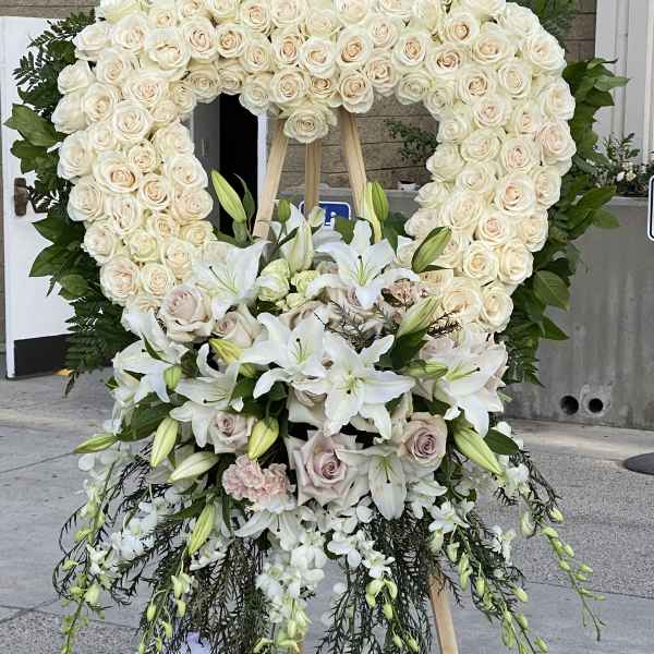 Large white floral standing heart on an easel with lilies and roses