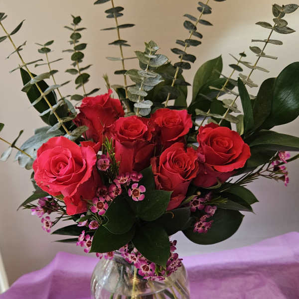 Red roses in a clear glass vase with pink filler flowers