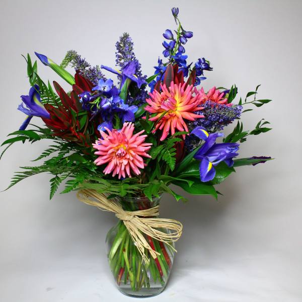 Colorful bouquet of pink, blue, and purple flowers in a glass vase