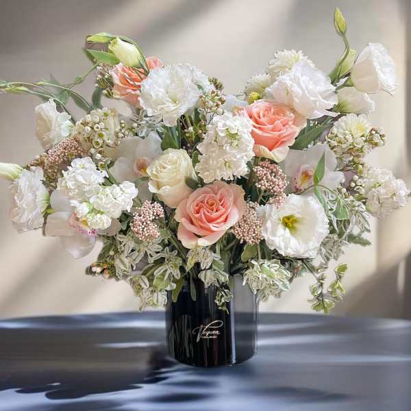 Large bouquet of white and blush flowers in a black vase