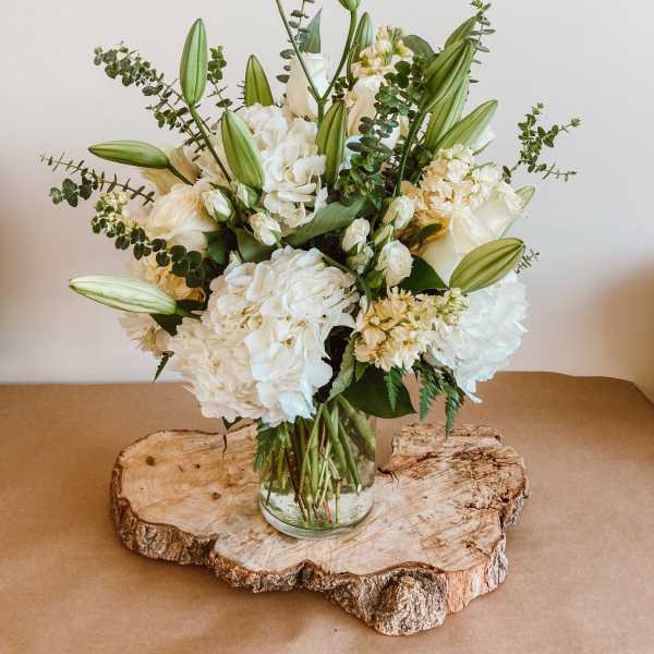 White floral arrangement in a glass vase with tall lily buds