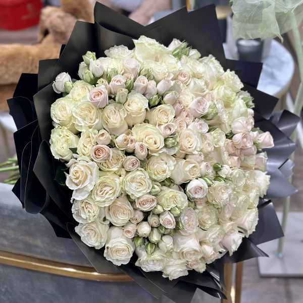 Large bouquet of white and pale pink roses wrapped in black paper