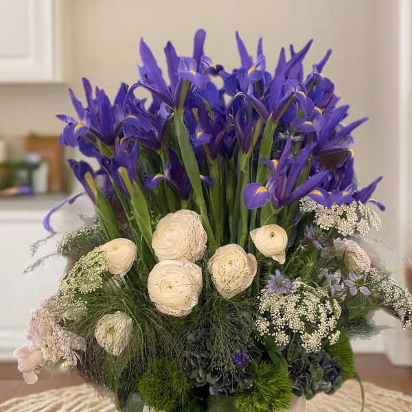 Purple iris arrangement with white blooms in a low glass bowl