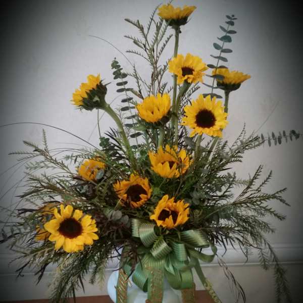 Tall sunflower arrangement in a white vase with green ribbon