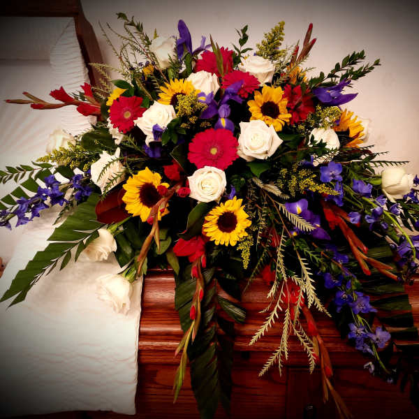 Large mixed floral spray with roses, sunflowers, and purple blooms