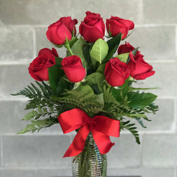 Bouquet of red roses in a glass vase with a red ribbon