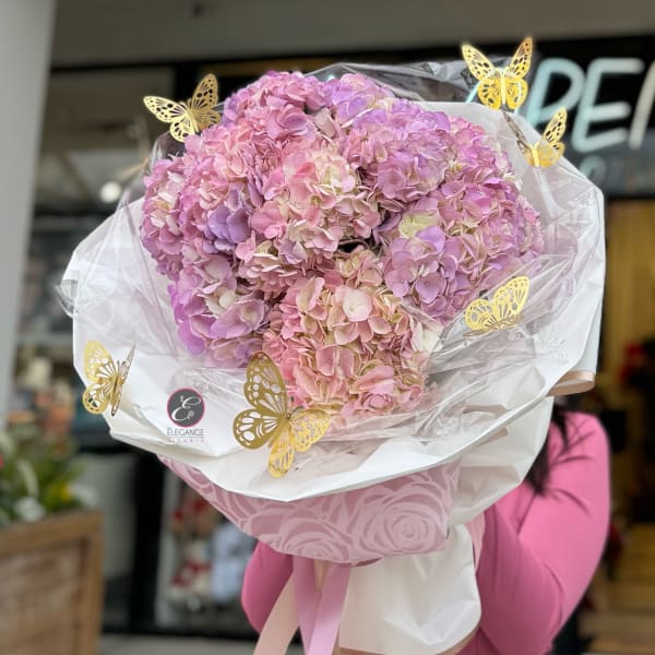 Large bouquet of pink and lavender hydrangeas wrapped in white paper