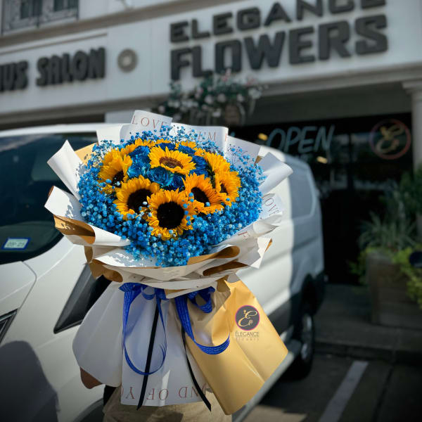 Bouquet of sunflowers and blue flowers wrapped in white paper