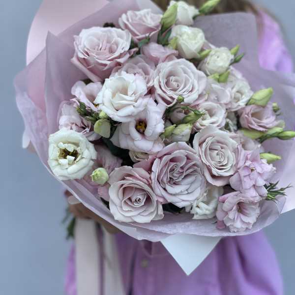 Bouquet of pale pink and white roses wrapped in lavender paper