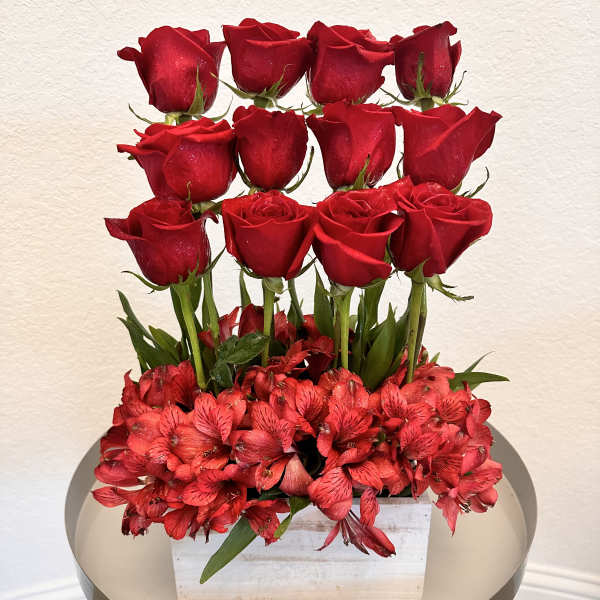Red roses arranged above red alstroemeria in a white box