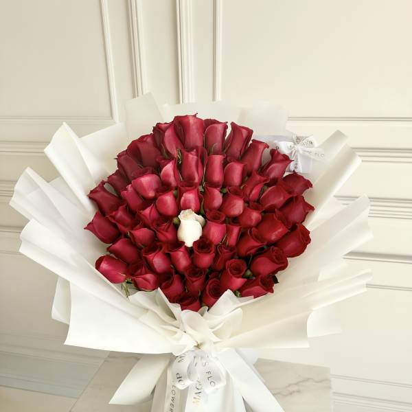 Bouquet of red roses wrapped in white paper with one white rose
