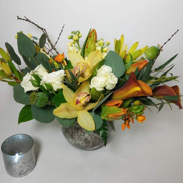Mixed floral arrangement with yellow orchids, white roses, and orange callas in a vase