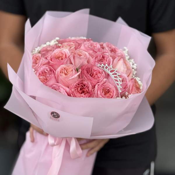 Pink rose bouquet wrapped in pale pink paper with a tiara pick