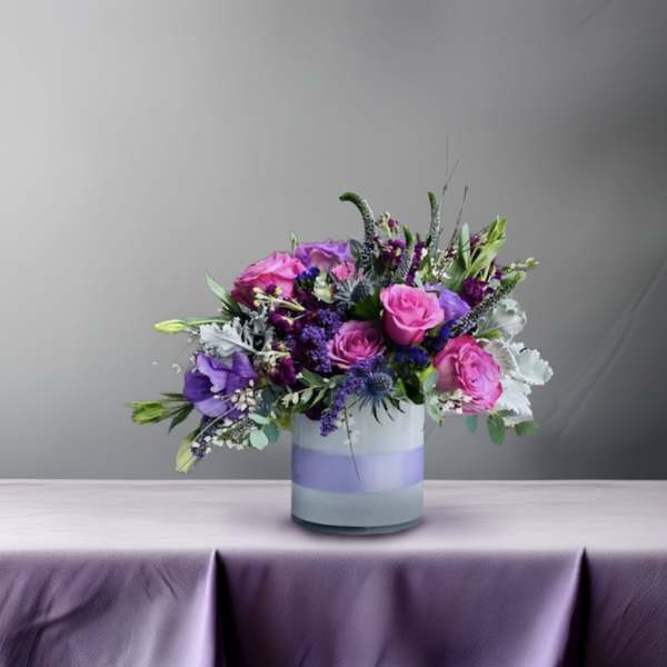 Pink and purple flower arrangement in a striped glass vase