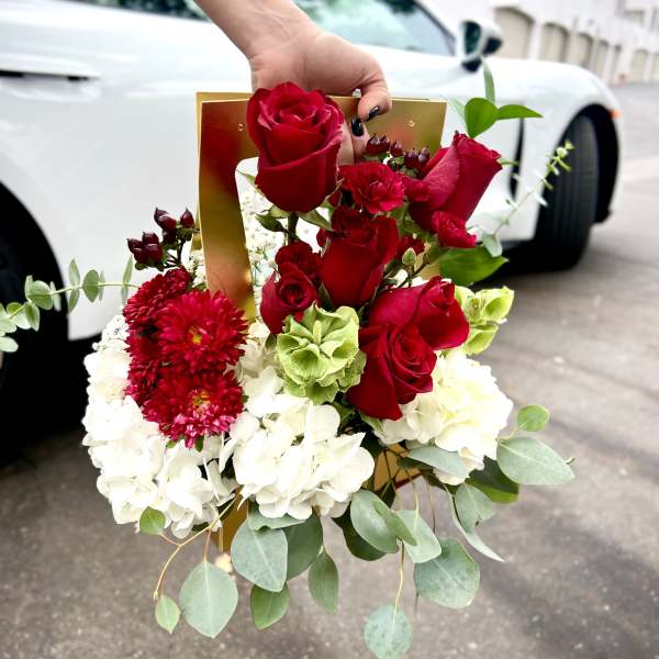 Hand holding a bouquet of red roses and white hydrangeas