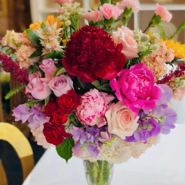 Mixed bouquet of pink, red, and purple flowers in a clear glass vase
