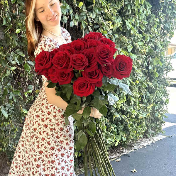 Woman holding a large bouquet of red roses