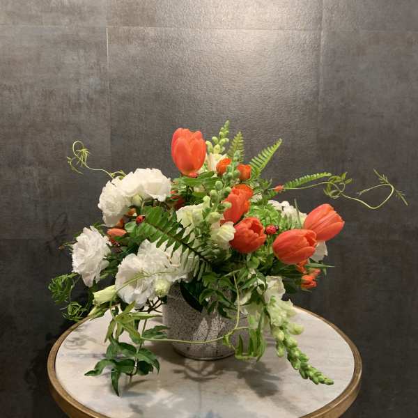 Orange tulips and white carnations in a textured vase