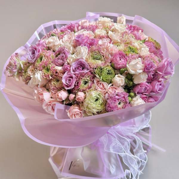 Large bouquet of pink, white, and green flowers wrapped in lavender paper