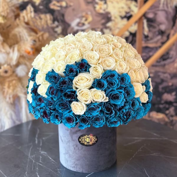Round bouquet of cream and blue roses in a gray hat box
