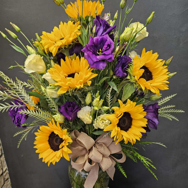 Bouquet of yellow sunflowers and purple lisianthus in a glass vase