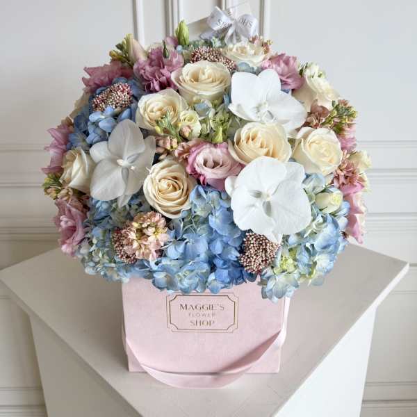 Pastel bouquet of roses, hydrangeas, and white orchids in a pink box