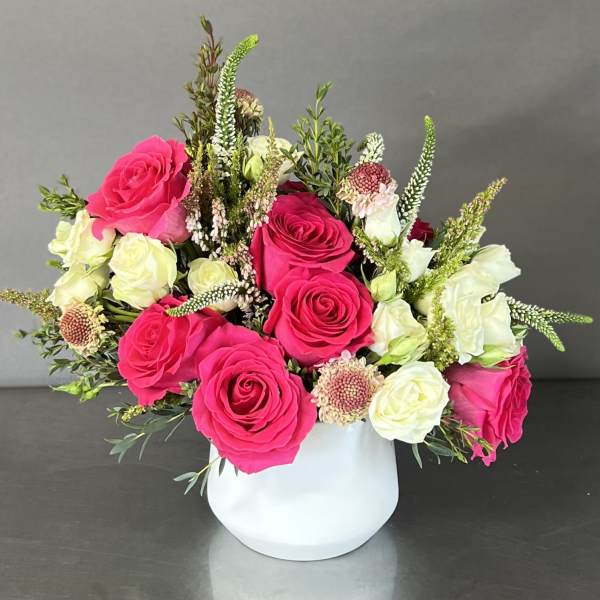 Pink and white roses arranged in a white vase