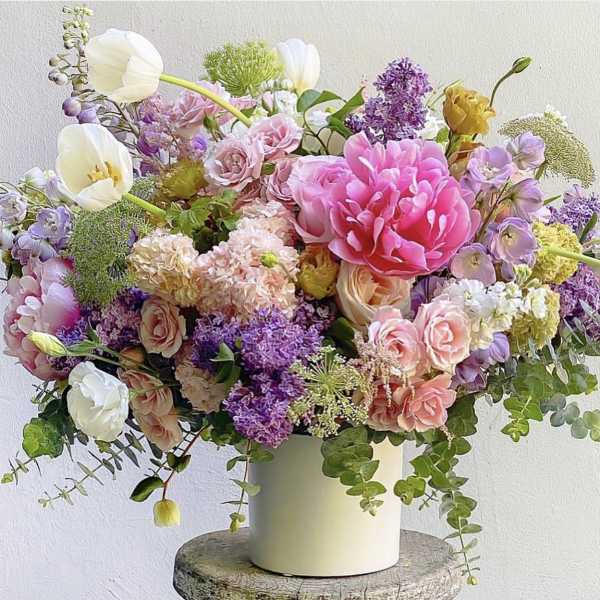 Mixed bouquet of pink, purple, and white flowers in a white vase