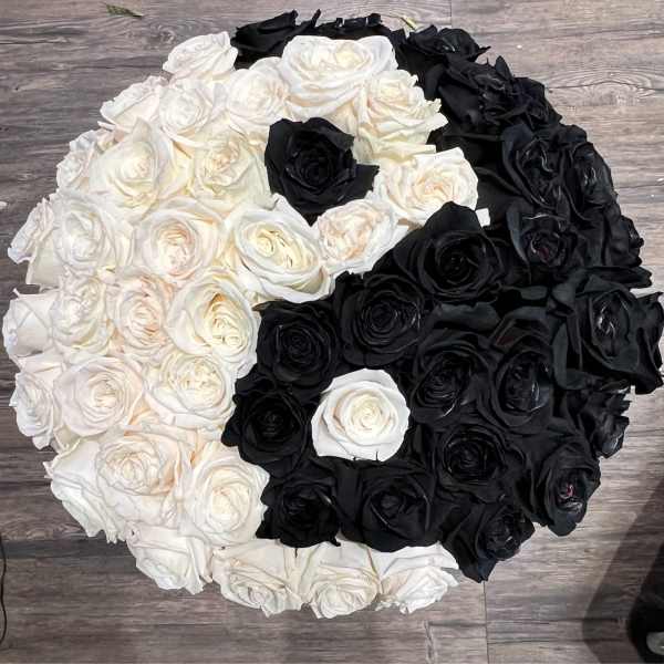 Round arrangement of white and black roses on a wood floor