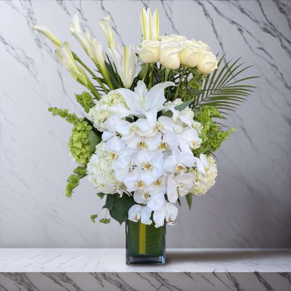 White orchids and roses in a clear glass vase