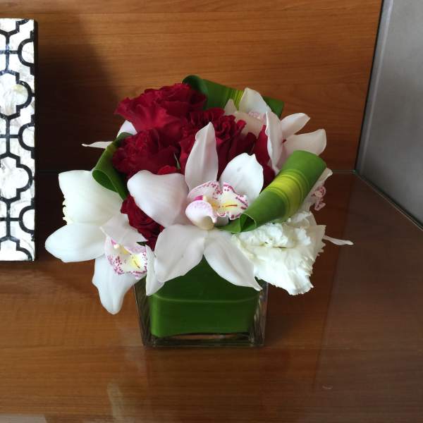 Bouquet of red and white flowers in a square glass vase
